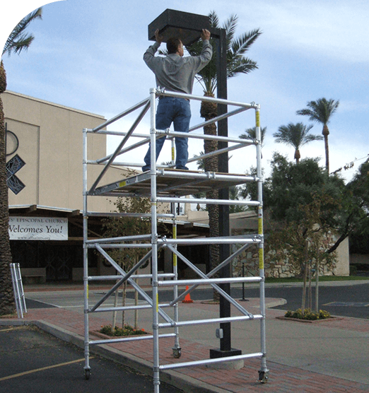Two people standing on top of a metal scaffold outdoors.